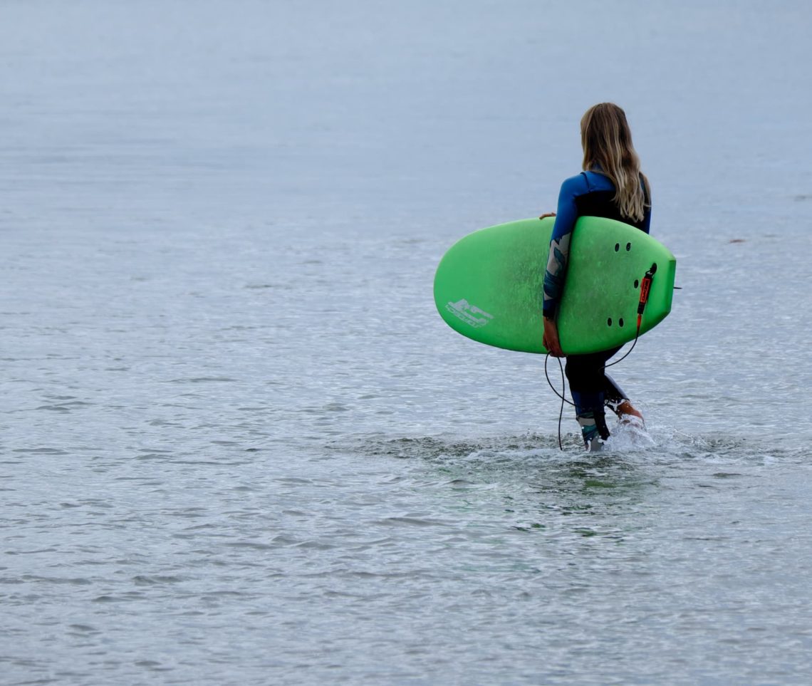 Une jeune apprentie surfeuse se met à l'eau pour un cours de surf