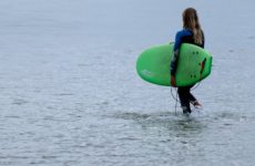 Une jeune apprentie surfeuse se met à l'eau pour un cours de surf