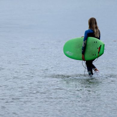 Une jeune apprentie surfeuse se met à l'eau pour un cours de surf